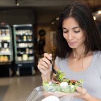 happy woman eating a salad on the go - junk food stock pictures, royalty-free photos & images