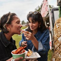 happy woman feeding female friend - food stock pictures, royalty-free photos & images