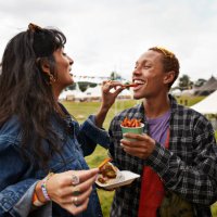 happy woman feeding street food to boyfriend - concert stock pictures, royalty-free photos & images