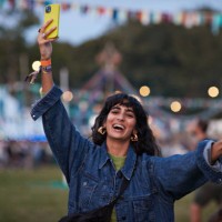 happy woman photographing through phone while dancing - concert stock pictures, royalty-free photos & images