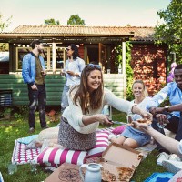 happy woman serving pizza to friends in backyard during summer party - junk food stock pictures, royalty-free photos & images