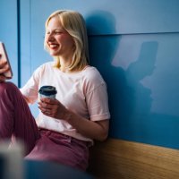 happy woman sitting in a cafe and looking at mobile phone - junk food stock pictures, royalty-free photos & images