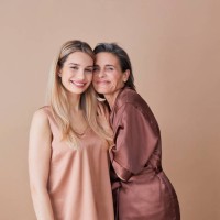 happy woman standing cheek to cheek with daughter against beige background - fashion stock pictures, royalty-free photos & images