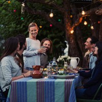 happy woman talking to friends sitting at dinner table in yard - garden decoration stock pictures, royalty-free photos & images