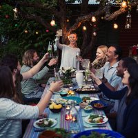 happy woman toasting drink to friends at dining table while enjoying outdoor dinner party - garden decoration stock pictures, royalty-free photos & images