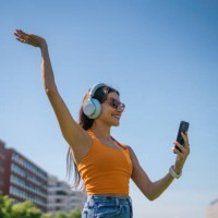 happy woman wearing headphones and using phone in the city - fashion stock pictures, royalty-free photos & images