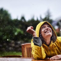 happy woman wearing raincoat during heavy rain in garden - garden decoration photos et images de collection