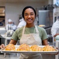 happy woman working at a bakery holding a tray of fresh bread - food stock pictures, royalty-free photos & images