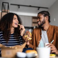 happy young couple eating fast food at home - junk food stock pictures, royalty-free photos & images