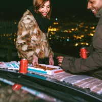 happy young couple having pizza on car bonnet against cityscape during night - junk food stock pictures, royalty-free photos & images