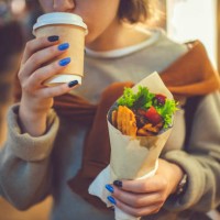 happy young girl drinking tea of coffee with street food in the evening city in summer - junk food stock pictures, royalty-free photos & images