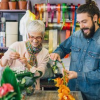 happy young man and a florist trimming flowers - garden decoration stock pictures, royalty-free photos & images