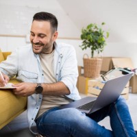 happy young man making a shopping checklist for his new apartment - home decoration stock pictures, royalty-free photos & images
