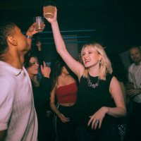 happy young woman and man toasting drinks while dancing against friends at nightclub - concert stock pictures, royalty-free photos & images