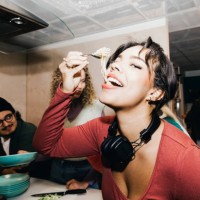 happy young woman eating noodles by friend in kitchen at college dorm - food stock pictures, royalty-free photos & images