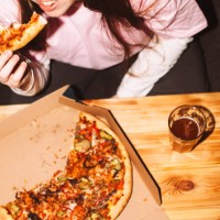 happy young woman eating pizza at house party - junk food stock pictures, royalty-free photos & images
