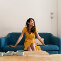 happy young woman sitting on couch looking sideways - home decoration stock pictures, royalty-free photos & images