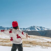 happy young woman with raised hands on the background of blue sky and winter mountains in winter looking at the landscape. christmas travel concept - travel photos et images de collection