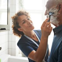 healthcare worker assisting senior man in shaving - hairstyle stock pictures, royalty-free photos & images