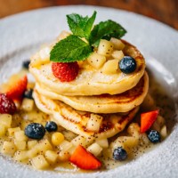 hearty stack of pancakes with maple syrup, fresh strawberry and blueberry on the plate - junk food stock pictures, royalty-free photos & images