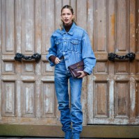 Helena Bordon wears golden earrings, lipstick, a brown turtleneck pullover , a blue oversized denim jacket, blue gathered denim pants / jeans ,...