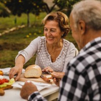 heureux couple de personnes âgées assis à table dans leur cour arrière, se liant et soupant - garden decoration photos et images de collection