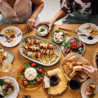 high angle shot of anonymous group of friends having lunch together at the dining table - food stock pictures, royalty-free photos & images