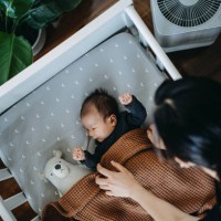 high angle shot of loving young asian mother taking care and tucking in her newborn baby daughter into crib in the nursery. love, care and tenderness. motherhood, parenthood concept - home decoration stockfoto's en -beelden