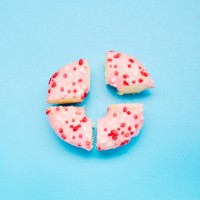 high angle view of a donut divided into four parts on blue background, symbol for pie chart - junk food stock pictures, royalty-free photos & images