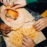 high angle view of friends eating burger and french fries at table in cafe - junk food stock pictures, royalty-free photos & images