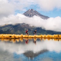 hikers reflection of mount taranaki egmont in natural lake middle - travel stock pictures, royalty-free photos & images