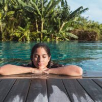 hispanic woman at hotel tropical resort sunbathing with palm trees in background - travel stock pictures, royalty-free photos & images
