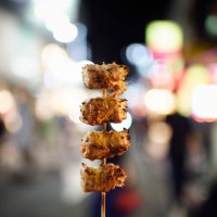 holding a bbq skewer on a street at night - junk food stock pictures, royalty-free photos & images