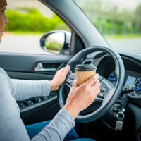 holding disposable coffee cup while driving - junk food stock pictures, royalty-free photos & images