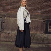 Hollie Mercedes Peters wears black long balloon skirt, white shirt, black tie, black mini bag and black shoes decorated with crystals outside the...
