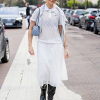 Hollie Mercedes Peters wears white net polo shirt, skirt, blue bag, black boots, sunglasses outside Lacoste during the Womenswear Fall/Winter...