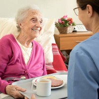 home caregiver with senior adult woman, serving a meal - food stock pictures, royalty-free photos & images