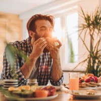 homme barbu ayant un sandwich pour le petit déjeuner à la maison. - food photos et images de collection