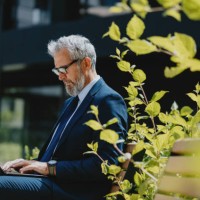 homme d’affaires senior travaillant sur un ordinateur portable à l’extérieur dans un jardin urbain - garden decoration photos et images de collection