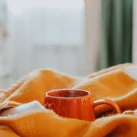 hot tea with steam in orange cup on bed in bedroom. copy space. cozy autumn or winter concept. - home decoration stock pictures, royalty-free photos & images