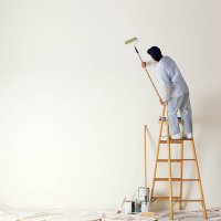 house painter standing on ladder painting a large wall - home decoration stock pictures, royalty-free photos & images