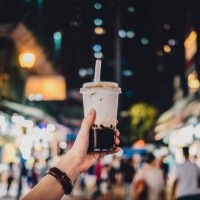 human hand holding a bottle of iced cold bubble tea against busy city street at night - junk food stock pictures, royalty-free photos & images