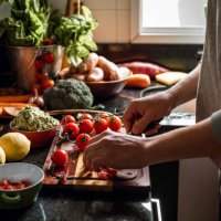 human hands slicing tomatoes over a wooden table for a vegan meal - food stock pictures, royalty-free photos & images