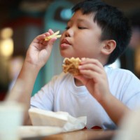 hungry boy eating burger with fries - junk food stock pictures, royalty-free photos & images