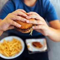 hungry young man holding tasty hamburger - junk food stock pictures, royalty-free photos & images