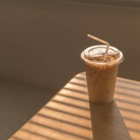ice latte coffee in disposable cup. cold drink on wood table and sunset behind window background. - junk food stock pictures, royalty-free photos & images