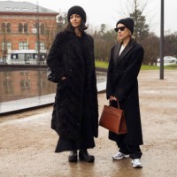 Ilenia Thoma wearing black long coat and hat and Tina Lundin wearing black long coat and brown bag outside MKDT in Copenhagen fashion week...