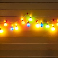 illuminated colorful string lights for party decoration at a yellow painted wooden wall in the evening - garden decoration stock pictures, royalty-free photos & images