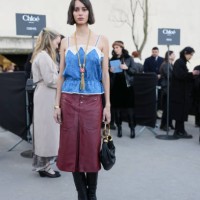 Iman Perez wears dark brown short hair, gold Chloe necklace, bright blue floral pattern lace top shiny burgundy bordeaux high slit midi leather...