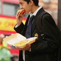 In this photo illustration school student Amir Shahin eats a burger and chips as part of his lunch which was brought from a fast food shop near his...